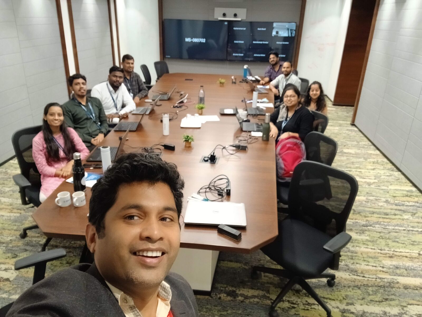 The cohort gathered around the conference table with laptops open during a hands-on lab.